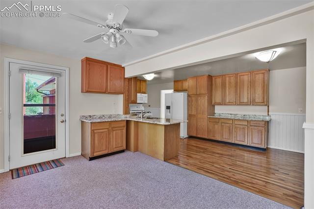 1404 West Cheyenne Road Colorado Springs, CO 80906 - Photo 28 of 50 Kitchen featuring ceiling fan, sink, kitchen peninsula, white appliances, and light wood-type flooring