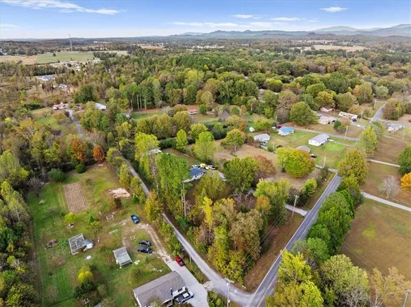 an aerial view of a residential houses with outdoor space and trees