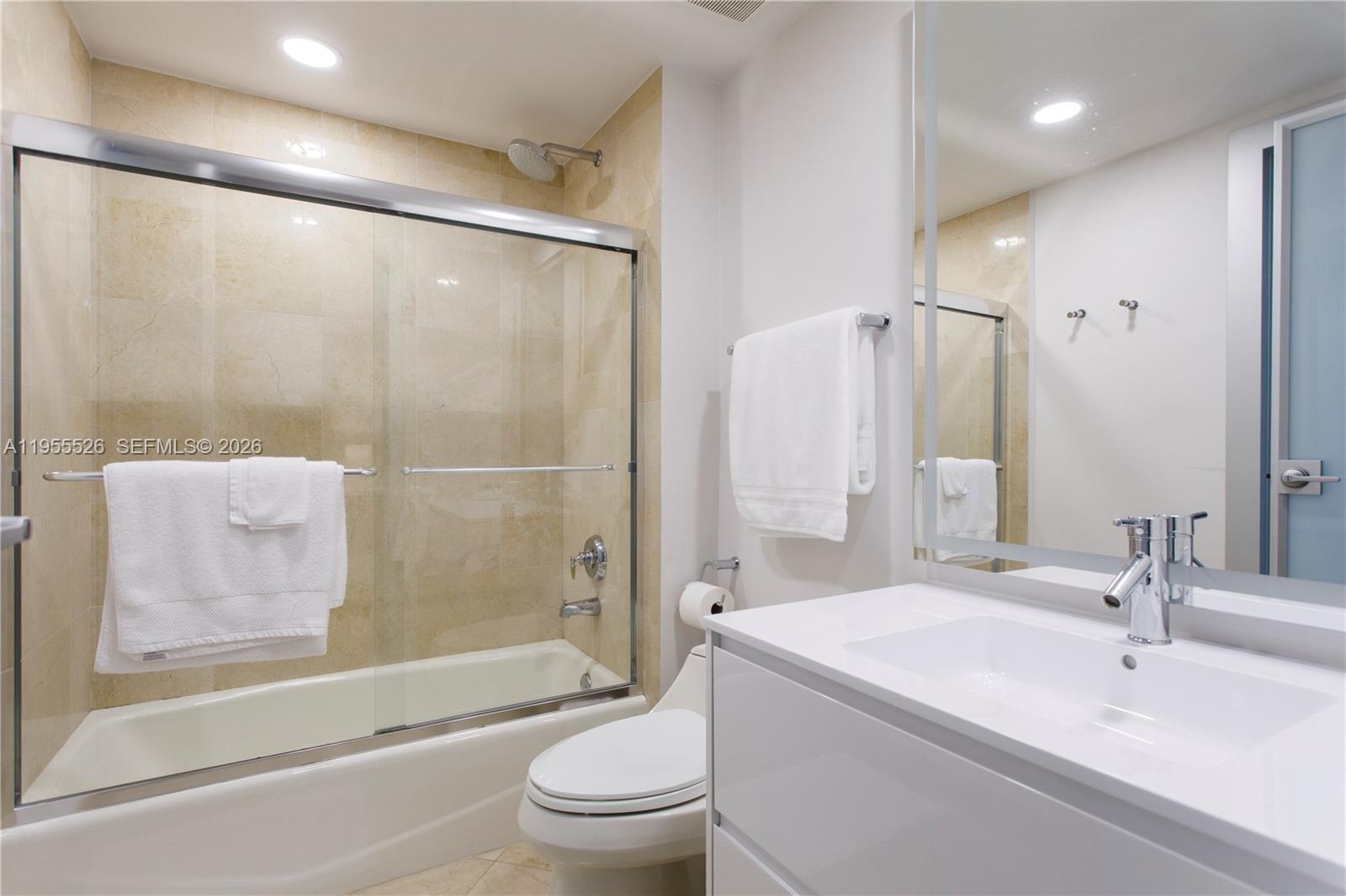 765 Crandon Boulevard, Unit 506 Key Biscayne, FL 33149 - Photo 9 of 19 a bathroom with a bathtub shower sink mirror vanity and toilet