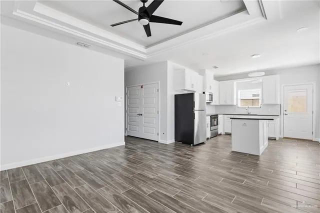 a view of a kitchen with stainless steel appliances wooden floor and a refrigerator