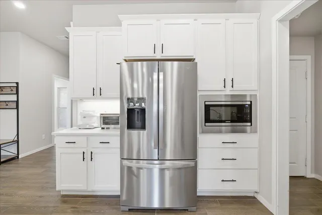 a kitchen with stainless steel appliances a refrigerator stove and white cabinets