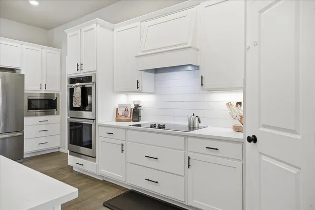 a kitchen with white cabinets and stainless steel appliances