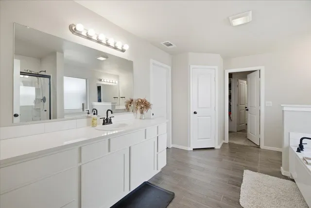 a spacious bathroom with a double vanity sink a mirror and a shower