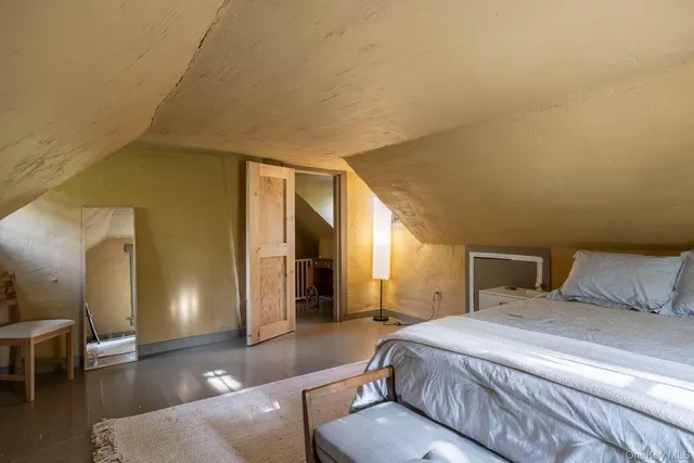 a spacious bedroom with a bed and wooden floor