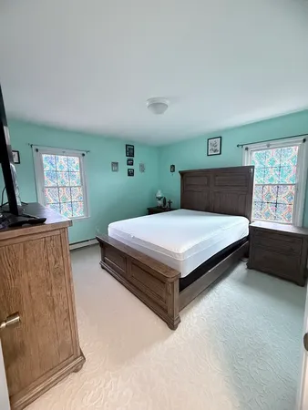 a bedroom with a bed and a flat tv screen on dresser