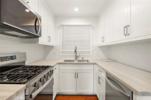 a kitchen with stainless steel appliances white cabinets and a stove a oven with wooden floor