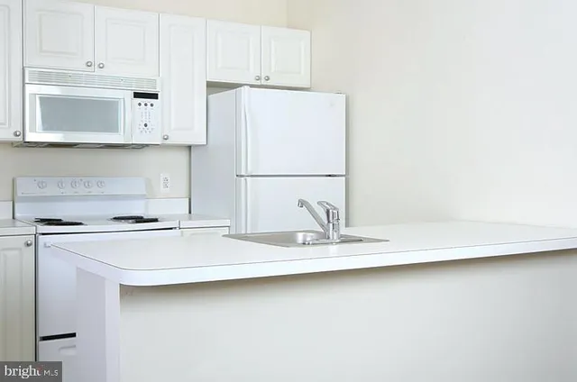 a kitchen with granite countertop white cabinets and white appliances