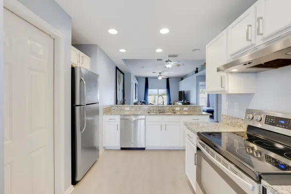 a kitchen with stainless steel appliances granite countertop a sink a stove a refrigerator and a cabinets