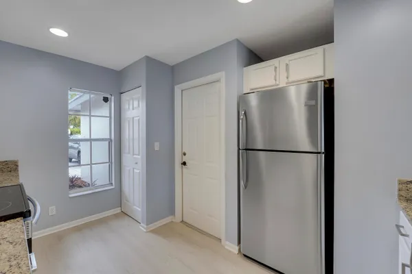 a view of an empty room with windows and refrigerator