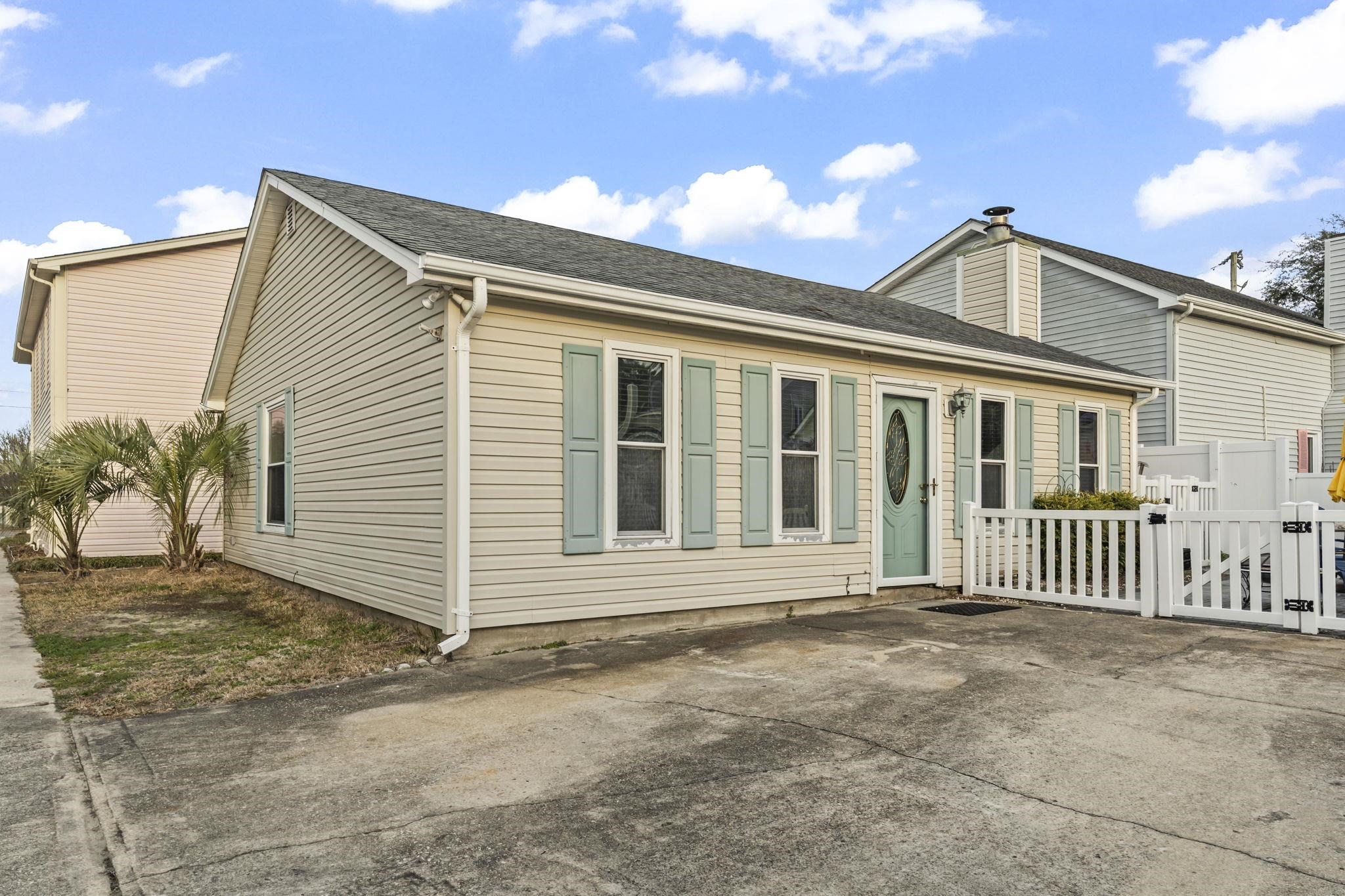 Rear view of house with a shingled roof, a patio area, and a gate