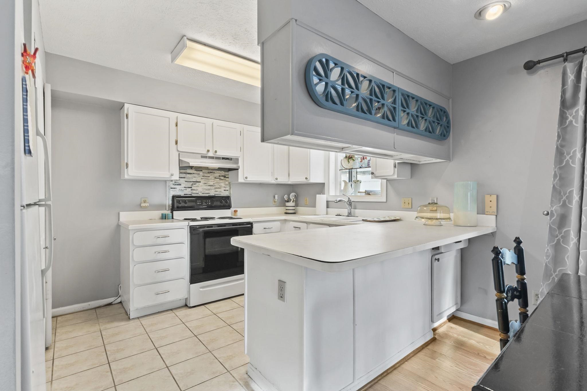 811 9th Avenue South North Myrtle Beach, SC 29582 - Photo 12 of 35 Kitchen with white appliances, white cabinets, a peninsula, tasteful backsplash, and light countertops
