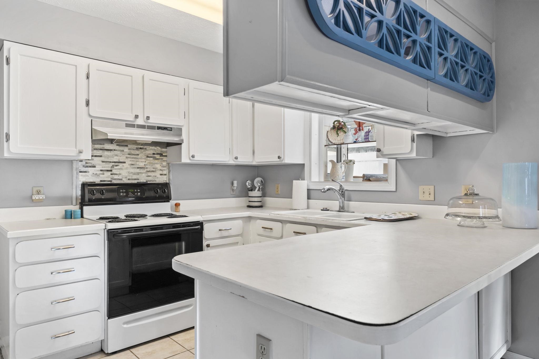 811 9th Avenue South North Myrtle Beach, SC 29582 - Photo 13 of 35 Kitchen featuring a peninsula, white electric range oven, white cabinets, light countertops, and under cabinet range hood