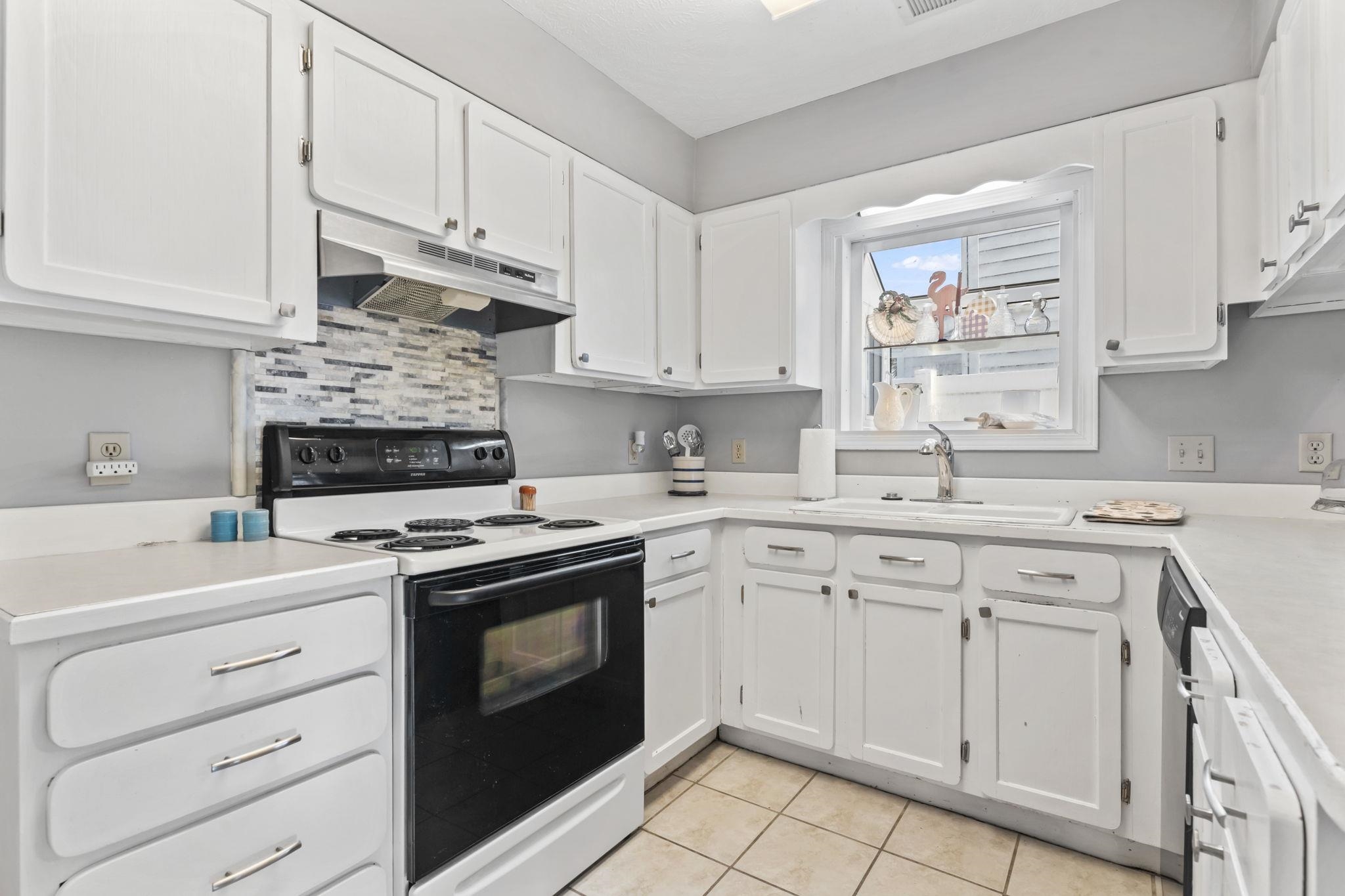 811 9th Avenue South North Myrtle Beach, SC 29582 - Photo 10 of 35 Kitchen with electric range oven, white cabinetry, under cabinet range hood, light countertops, and light tile patterned floors