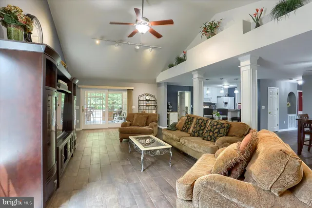 a living room with furniture a ceiling fan and a flat screen tv