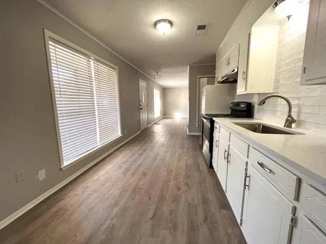 a view of a kitchen with a sink and wooden floor