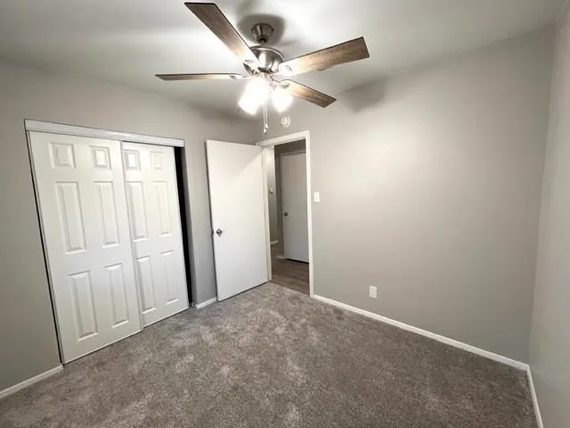 an empty room with closet and a ceiling fan