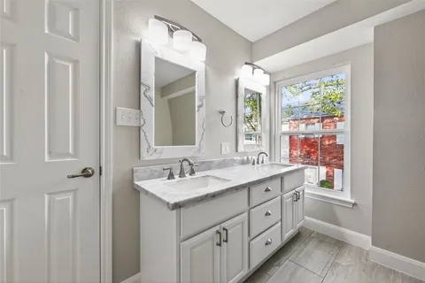 a spacious bathroom with a double vanity sink a mirror and next to a window