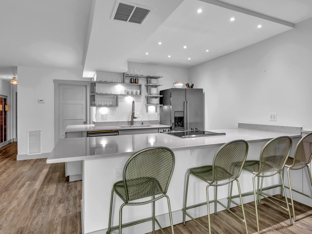 275 Date Palm Road, Unit 304 Vero Beach, FL 32963 - Photo 6 of 36 a kitchen with stainless steel appliances kitchen island granite countertop a table chairs in it and wooden floors