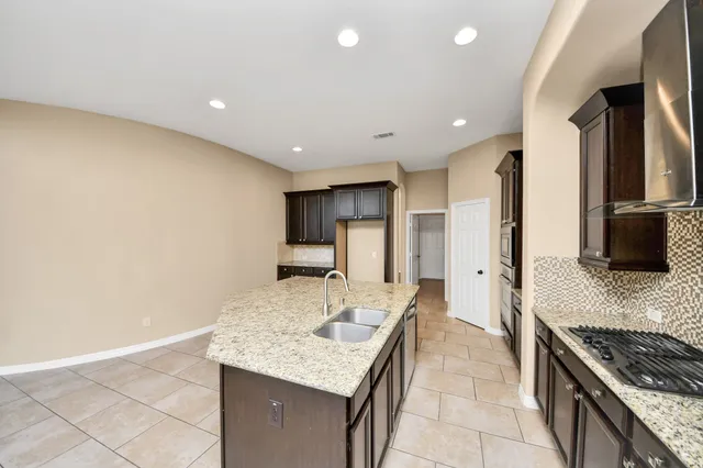 a kitchen with granite countertop a sink a stove and refrigerator