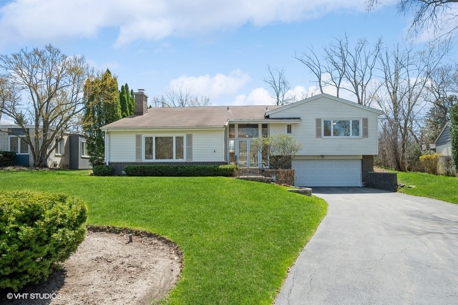 a front view of a house with a garden and trees
