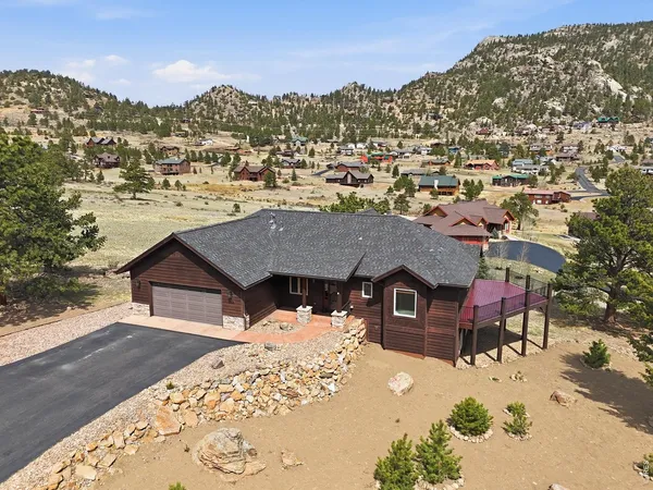 an aerial view of a house with a mountain