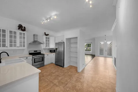 a kitchen with stainless steel appliances a refrigerator a sink a stove and white cabinets