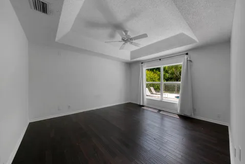 an empty room with wooden floor fan and windows