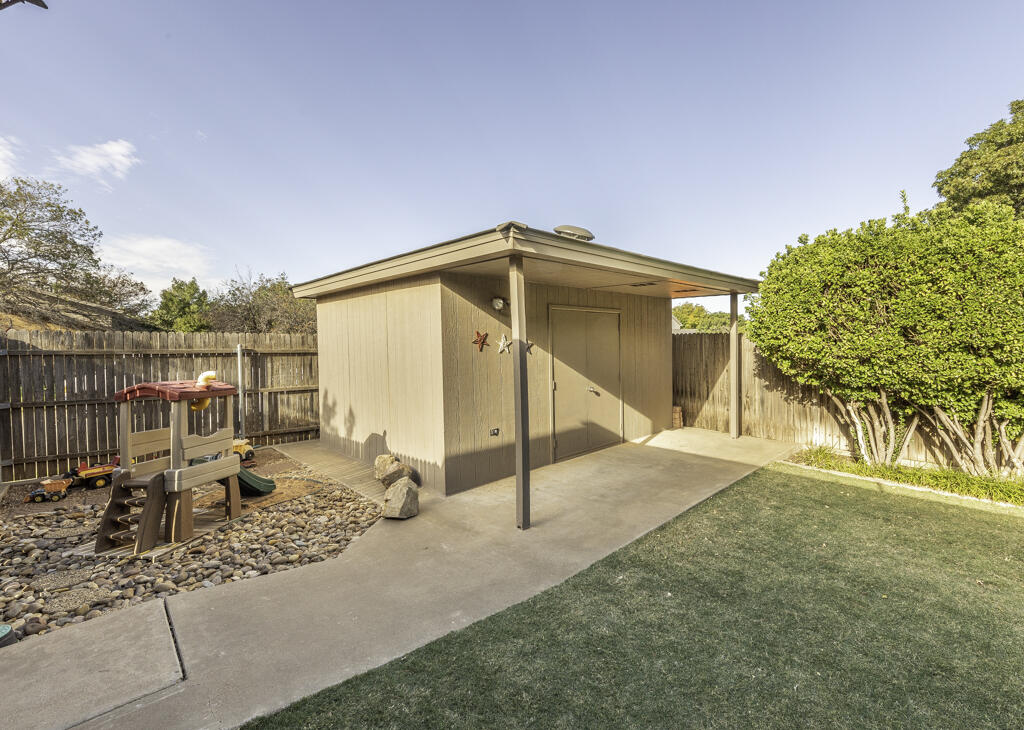 3620 93rd Street Lubbock, TX 79423 - Photo 31 of 33 a backyard of a house with table and chairs under an umbrella