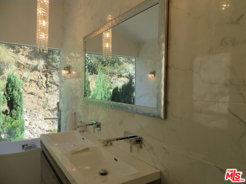 9659 Cedarbrook Drive Beverly Hills, CA 90210 - Photo 17 of 21 a bathroom with a granite countertop sink a mirror and a shower
