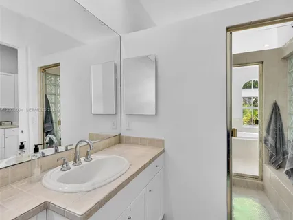 a spacious bathroom with a granite countertop tub sink a mirror a bathtub and next to a window