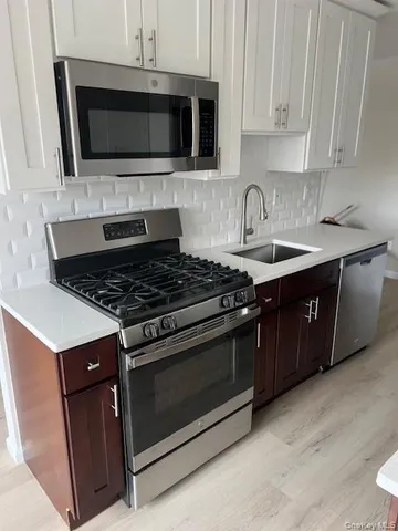 a kitchen with stainless steel appliances a stove a microwave a sink and cabinets