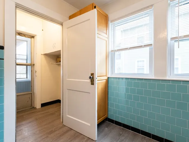 an empty room with wooden floor chandelier fan and windows
