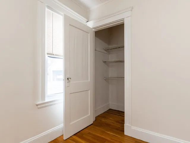 an empty room with wooden floor chandelier fan and windows