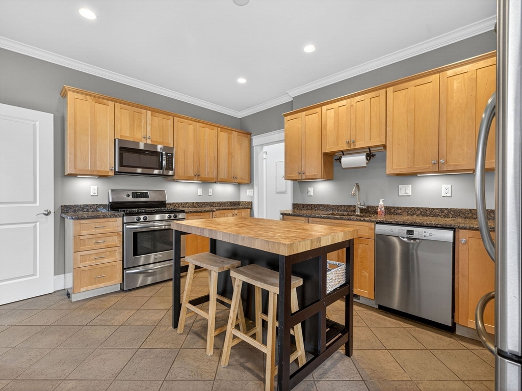 71 Parkton Road, Unit 2 Boston, MA 02130 - Photo 9 of 26 a kitchen with granite countertop a stove top oven microwave and a refrigerator