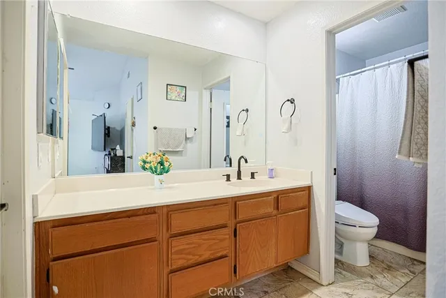 a bathroom with a double vanity sink toilet and shower