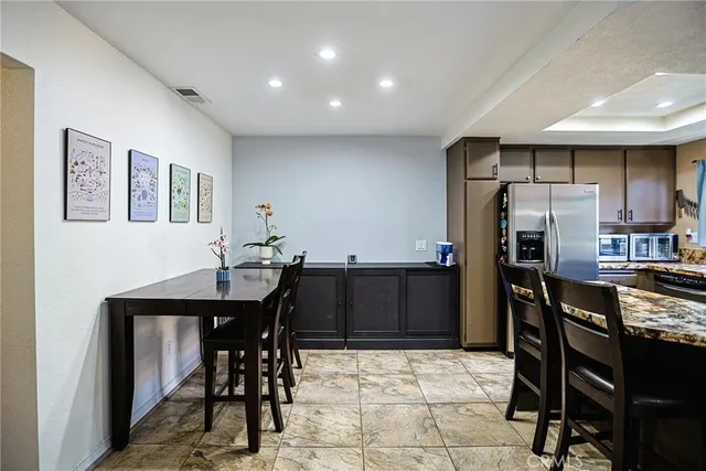 a kitchen with stainless steel appliances a dining table chairs and refrigerator