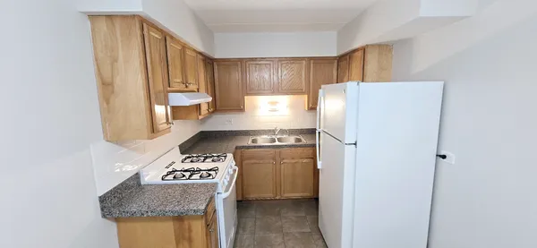 a kitchen with a refrigerator a stove top oven and cabinets