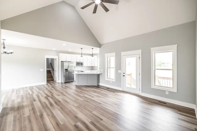 an empty room with chandelier fan and windows