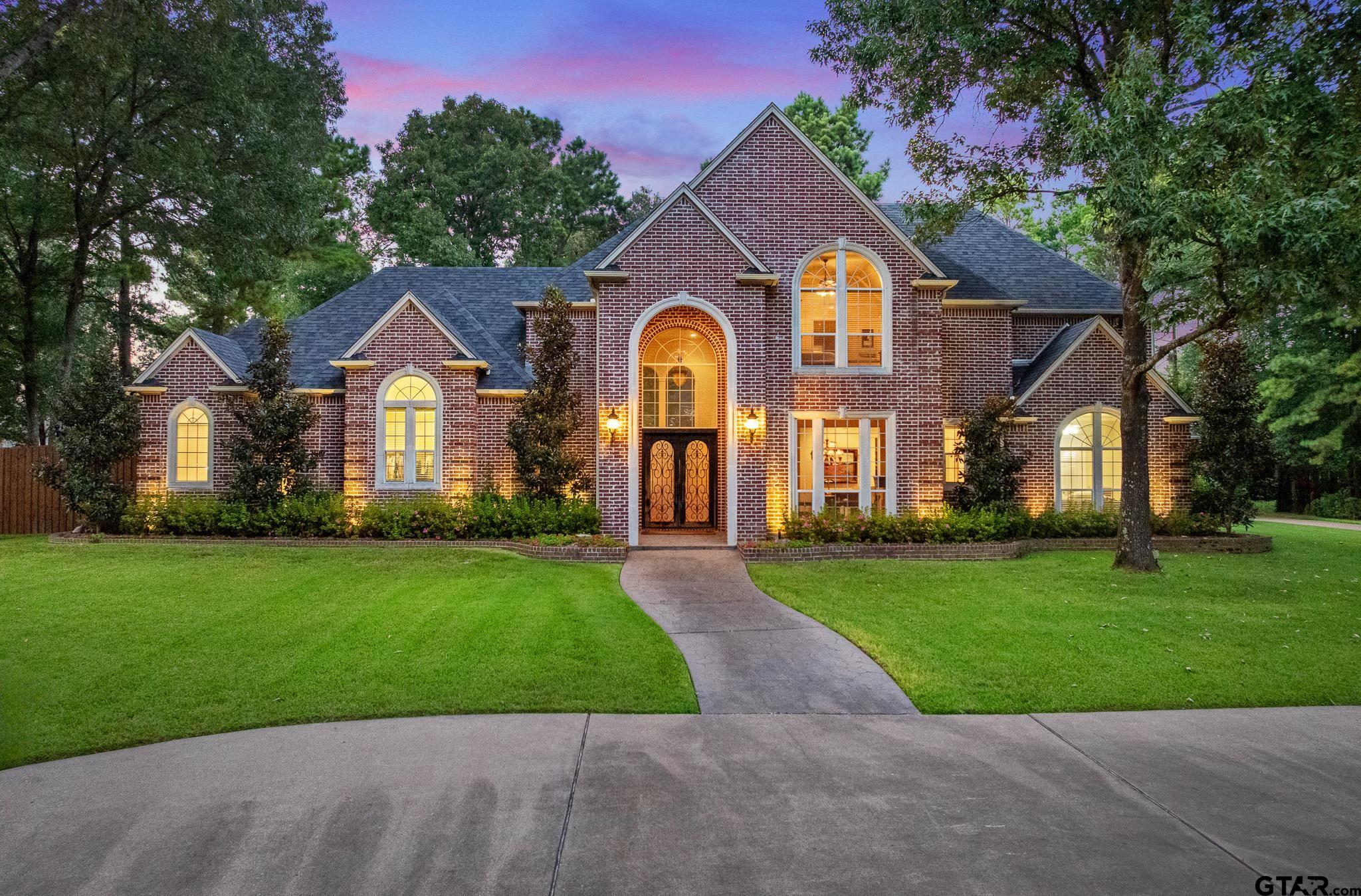 a front view of a house with a garden and trees