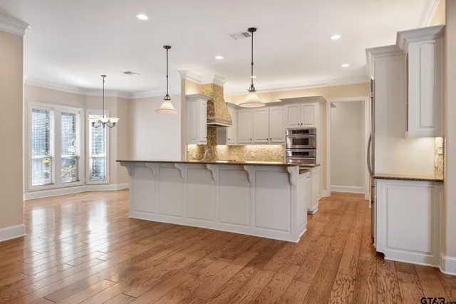 a kitchen with stainless steel appliances granite countertop a refrigerator a oven and a wooden floors