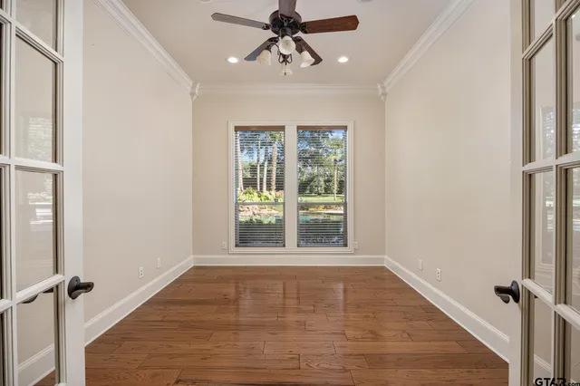 a view of empty room with wooden floor and fan