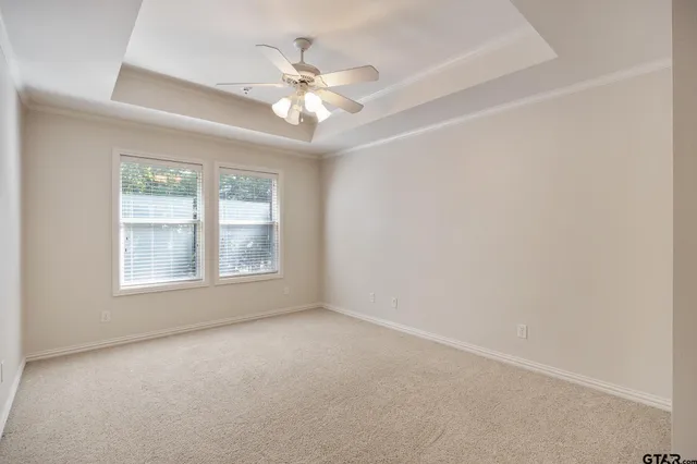 an empty room with a chandelier fan and windows