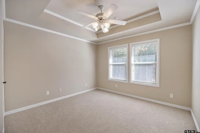 an empty room with windows and ceiling fan