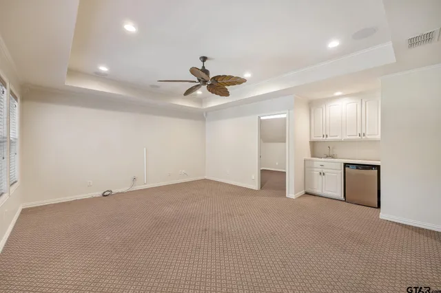 a view of an empty room with a ceiling fan and kitchen view