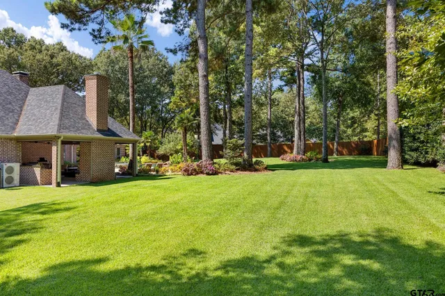 a view of a house with a big yard and large trees