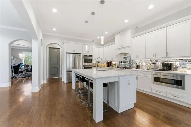 a kitchen with stainless steel appliances a sink stove and wooden floor