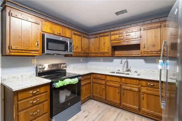 a kitchen with stainless steel appliances granite countertop wooden cabinets and a stove top oven