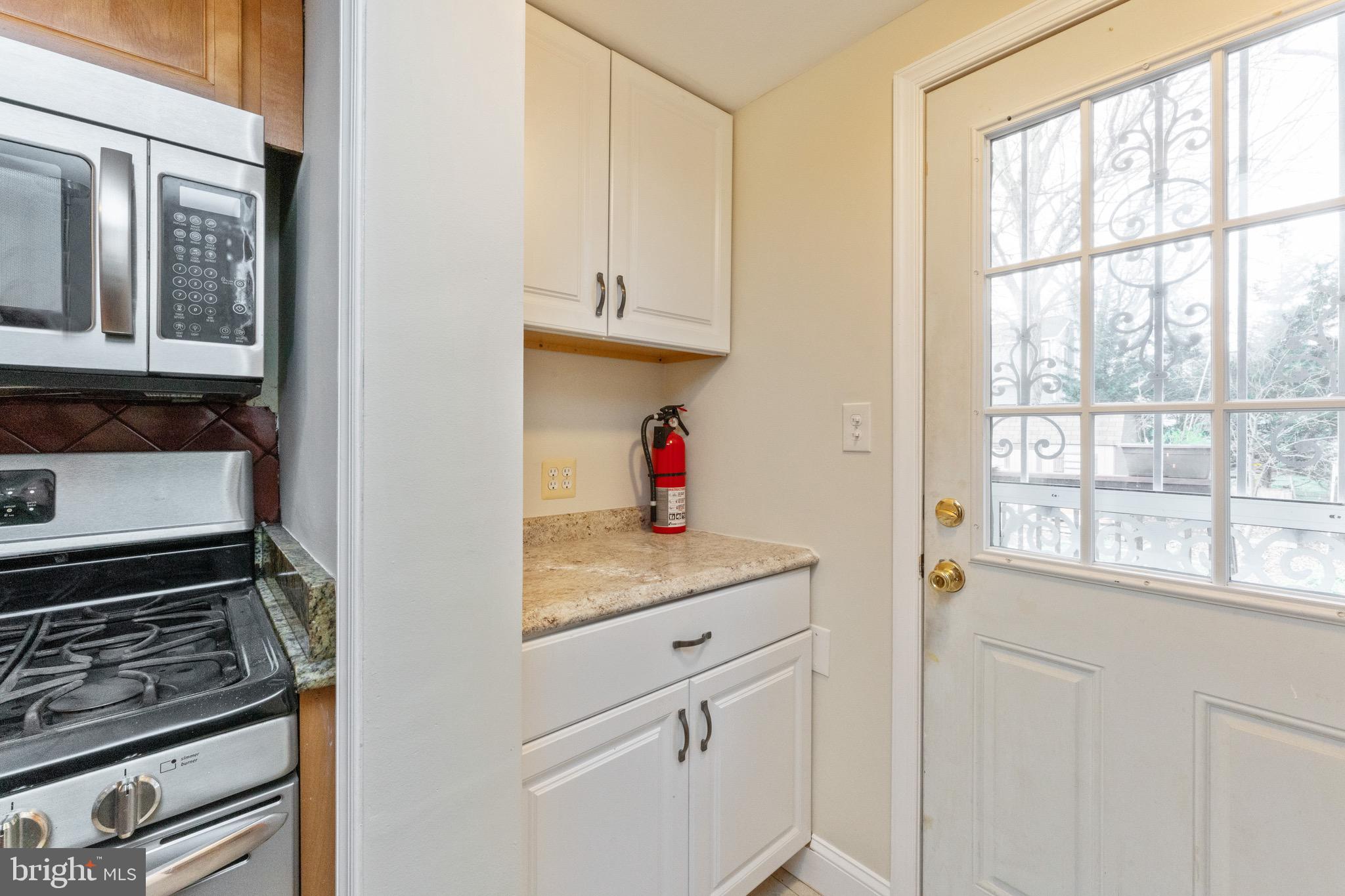 1609 Brisbane Street Silver Spring, MD 20902 - Photo 14 of 25 a kitchen with white cabinets and a stove