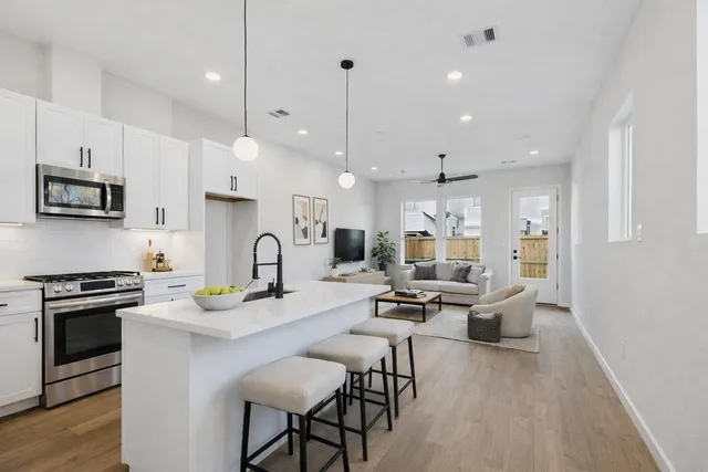 a open kitchen with stainless steel appliances granite countertop a stove a sink dishwasher a dining table and chairs with wooden floor