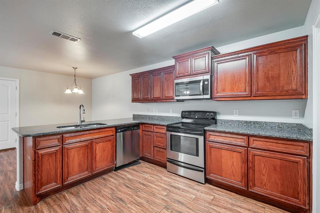 452 Canvas Court Crowley, TX 76036 - Photo 7 of 11 a kitchen with stainless steel appliances granite countertop wooden cabinets sink and stove top oven